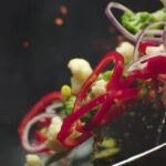 Closeup of Chef Preparing and Throwing Vegetable Mix on Frying Pan on Fire Preparation Fresh