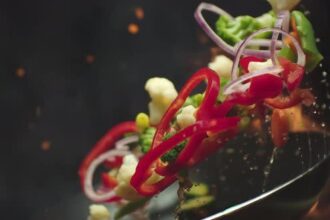 Closeup of Chef Preparing and Throwing Vegetable Mix on Frying Pan on Fire Preparation Fresh